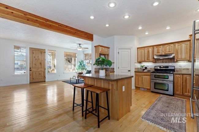 Kitchen featuring light wood-style floors, stainless steel appliances, tasteful backsplash, a kitchen island, and a kitchen breakfast bar | Image 20