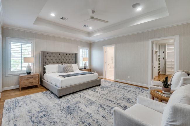 Bedroom with light wood finished floors, multiple windows, visible vents, and a raised ceiling | Image 13