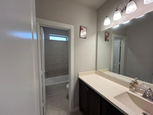 Bathroom featuring vanity, toilet, tile patterned floors, and washtub / shower combination | Image 18