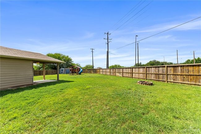Fenced backyard with a playground and a fire pit | Image 28