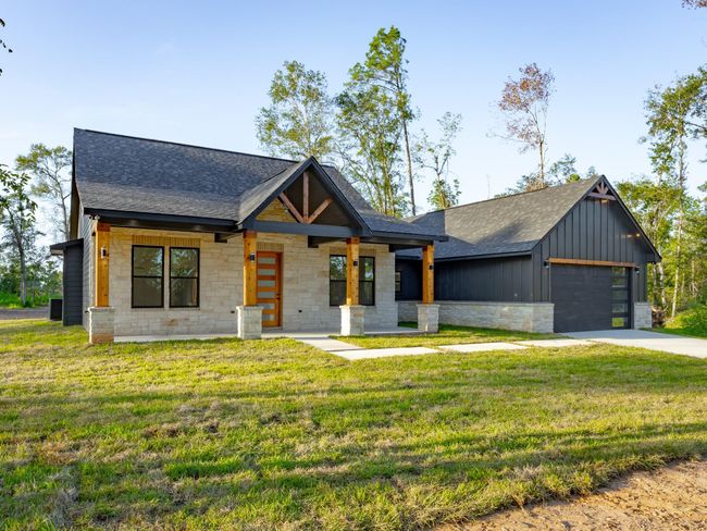 This modern farmhouse radiates curb appeal with its limestone and board-and-batten façade, exposed cedar beams, and expansive front porch—captured beautifully in the soft evening light. | Image 38