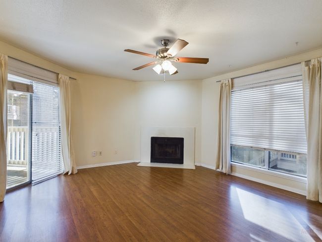 Unfurnished living room with baseboards, wood finished floors, a ceiling fan, and a fireplace with flush hearth | Image 7