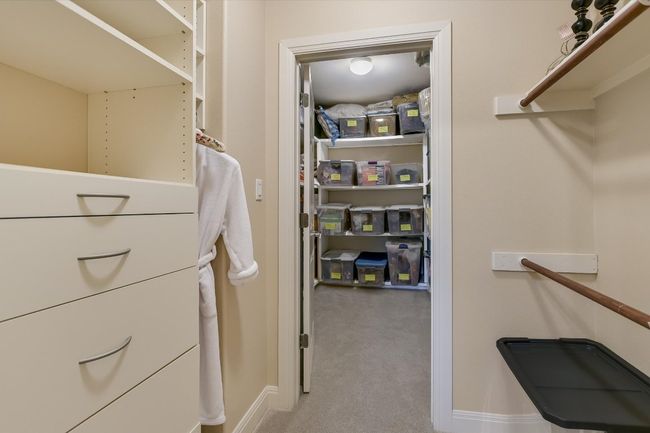 Back-to-back Walk in closet with carpet floors and storage shelving and drawers. | Image 25