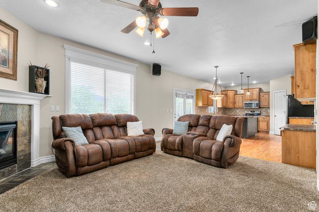 Living area with recessed lighting, a tiled fireplace, ceiling fan, light carpet, and baseboards | Image 7