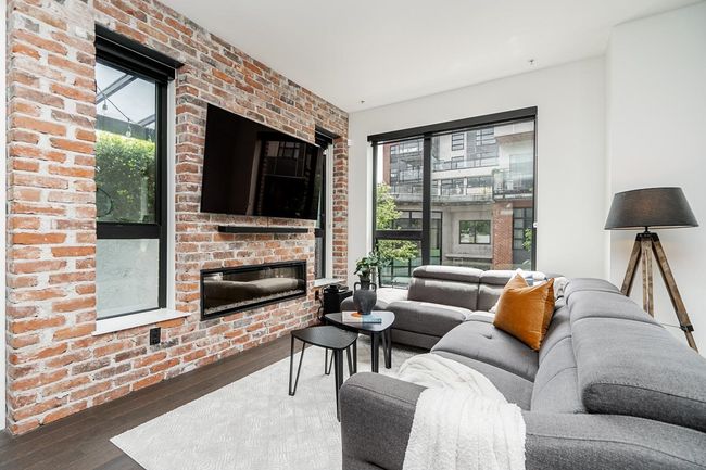 Living area with hardwood / wood-style floors and brick wall | Image 12