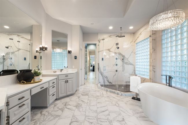 Bathroom with a marble finish shower, vanity, a soaking tub, marble finish flooring, and a chandelier | Image 20