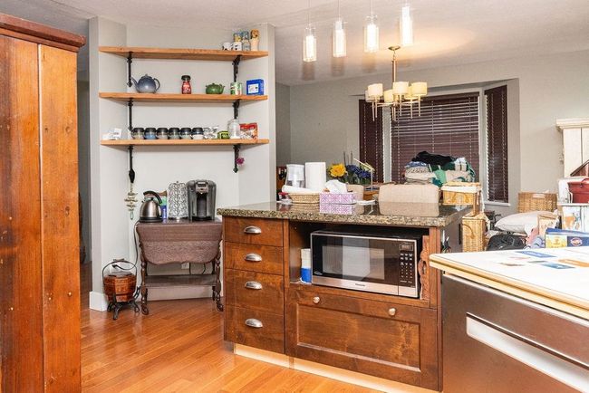 Kitchen featuring brown cabinetry, a notable chandelier, hanging light fixtures, and light wood finished floors | Image 10