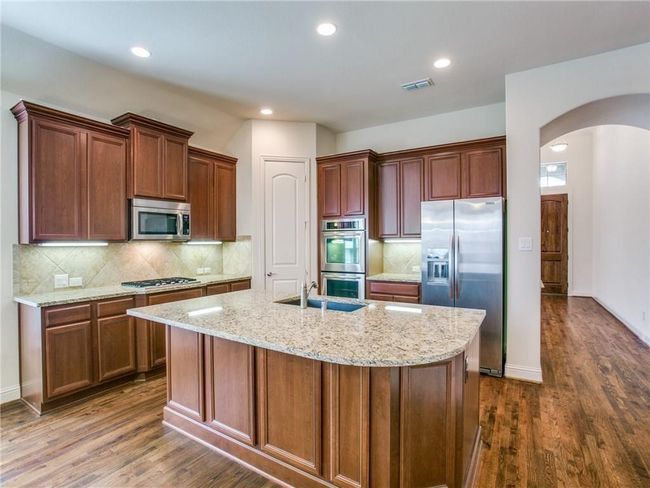 Kitchen with appliances with stainless steel finishes, a sink, arched walkways, dark wood-type flooring, and recessed lighting | Image 6