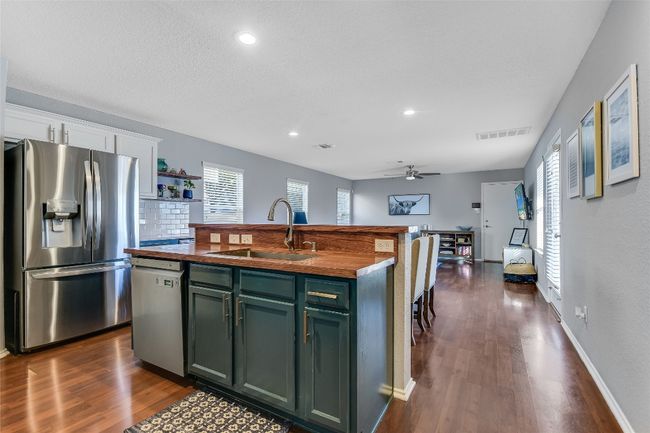 Kitchen with appliances with stainless steel finishes, wooden counters, green cabinetry, a ceiling fan, and dark wood-style floors | Image 9