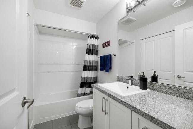 Full bathroom with visible vents, shower / bath combo with shower curtain, toilet, tile patterned flooring, and vanity | Image 34