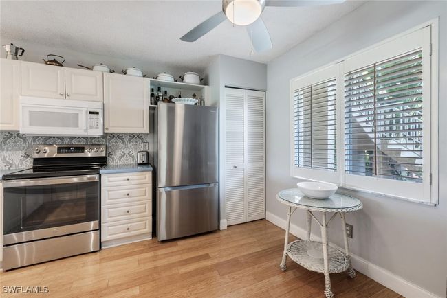 Kitchen featuring backsplash, a ceiling fan, light wood-type flooring, stainless steel appliances, and baseboards | Image 6