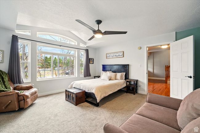Bedroom with carpet flooring, vaulted ceiling, a textured ceiling, and ceiling fan | Image 17