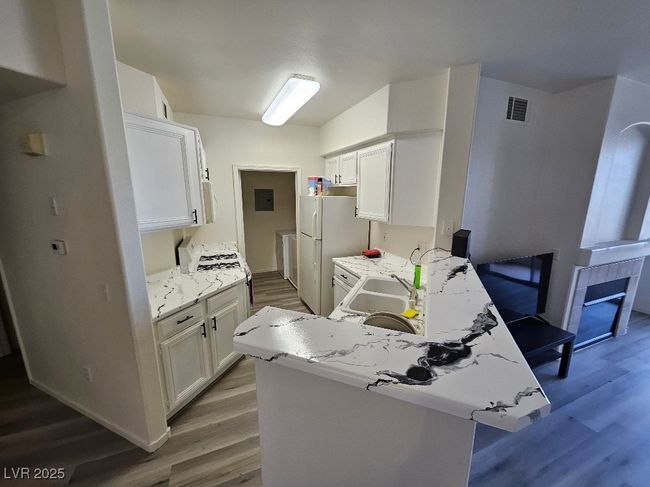 Kitchen with white cabinets, wood finished floors, and visible vents | Image 23