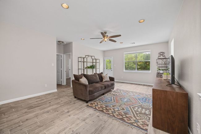 Living area featuring visible vents, baseboards, recessed lighting, light wood finished floors, and a ceiling fan | Image 5