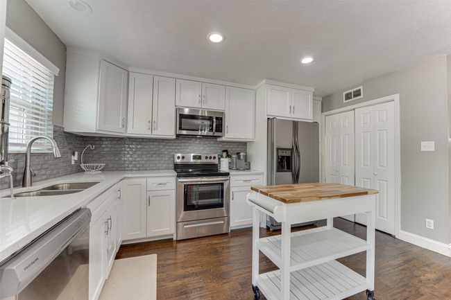Kitchen with visible vents, a sink, dark wood finished floors, stainless steel appliances, and decorative backsplash | Image 10