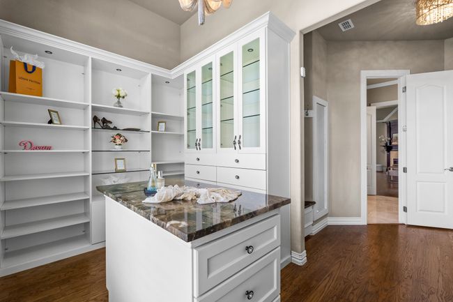 Walk in closet with a chandelier and dark wood finished floors | Image 20