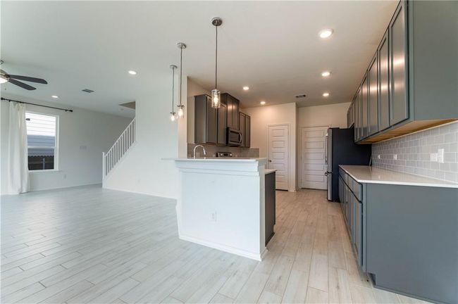 Kitchen featuring appliances with stainless steel finishes, ceiling fan, open floor plan, tasteful backsplash, and light wood finished floors | Image 14