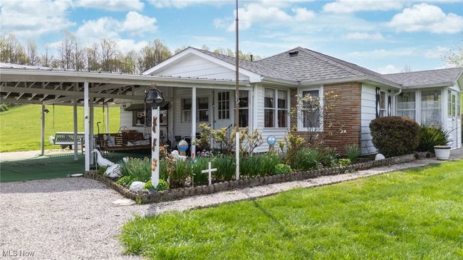 View of front of house with stone siding, a carport, a front yard, and roof with shingles | Image 26