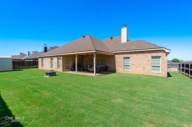Rear view of property with an outdoor fire pit, brick siding, a patio area, a chimney, and a shingled roof | Image 39