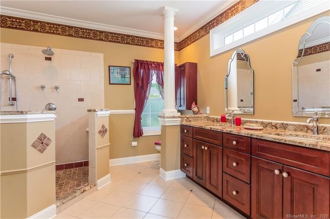 Primary bathroom is appointed with double sink, transom window, column and large walk-in shower. | Image 25