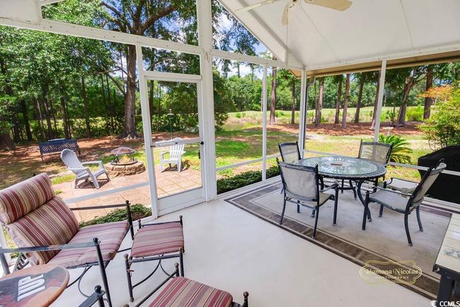 Sunroom / solarium featuring an outdoor fire pit, outdoor dining space, ceiling fan, lofted ceiling, and view of wooded area | Image 17