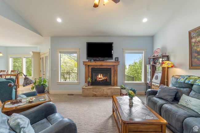 Carpeted living room featuring lofted ceiling, a high end fireplace, ceiling fan, recessed lighting, and baseboards | Image 13