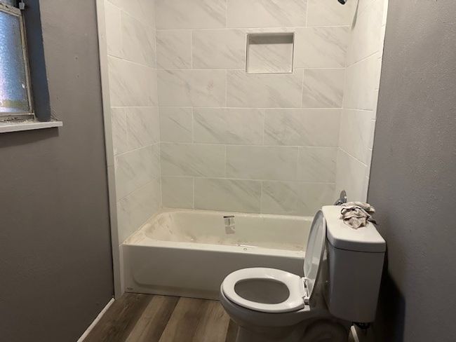 Bathroom featuring shower combination, toilet, and wood finished floors | Image 9