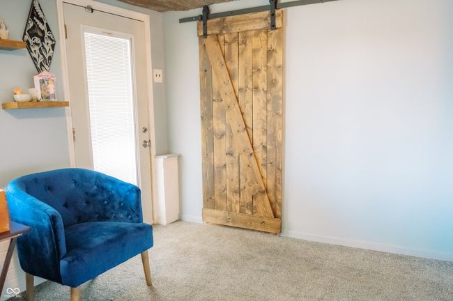 living area featuring carpet floors, baseboards, and a barn door | Image 14