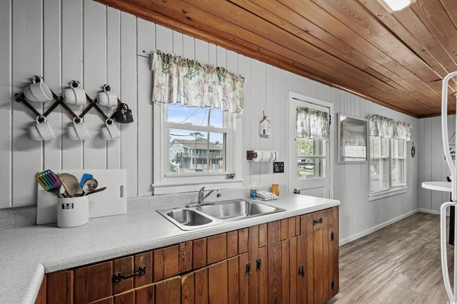 Kitchen with wood ceiling, a sink, light countertops, light wood-type flooring, and brown cabinets | Image 20