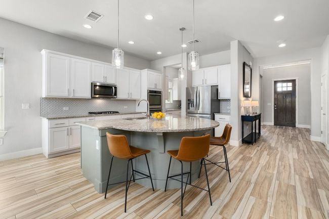 Kitchen with tile backsplash, a large island with sink, and stainless steel appliances | Image 6