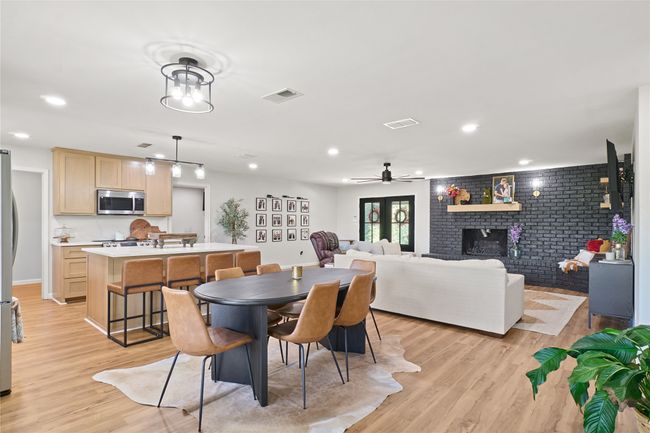 Dining space with brick wall, light wood-style floors, a brick fireplace, a ceiling fan, and recessed lighting | Image 8