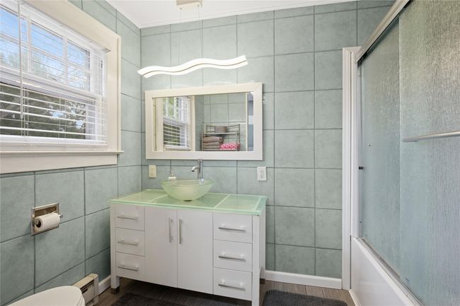 Full bath with vanity, baseboard heating, baseboards, enclosed tub / shower combo, and tile walls | Image 19