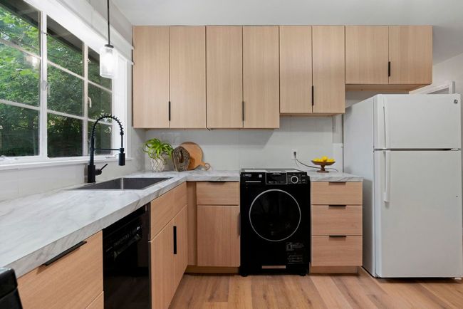 Views of the washer/dryer location and the abundant cabinetry throughout, providing plenty of space for your kitchen needs. | Image 9