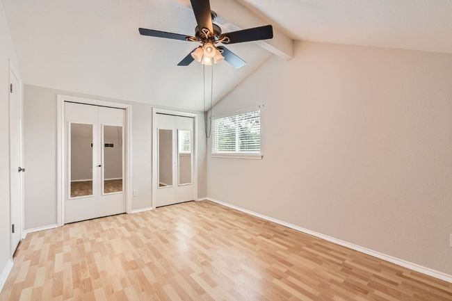 Unfurnished bedroom featuring baseboards, vaulted ceiling with beams, two closets, and light wood-style flooring | Image 19