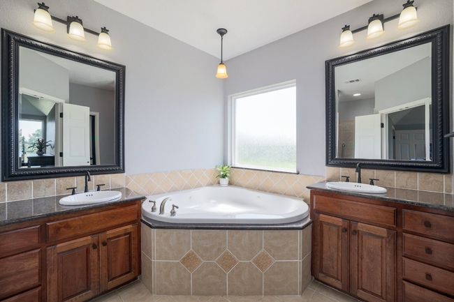Natural sunlight surrounds the dual vanities and garden tub | Image 19