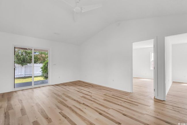 Empty room with vaulted ceiling and light wood finished floors | Image 7