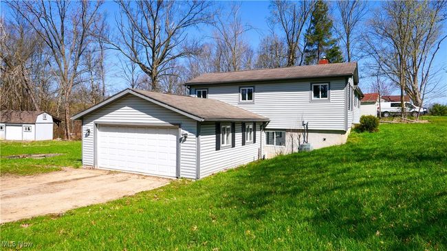 View of front facade featuring a detached garage, a chimney, a front lawn, and roof with shingles | Image 34