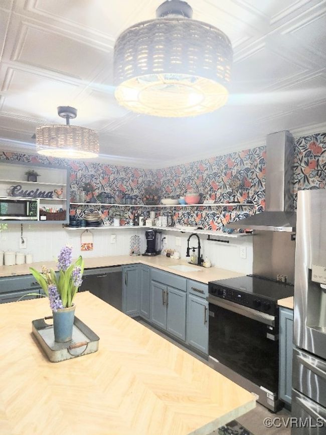 Kitchen featuring appliances with stainless steel finishes, wall chimney exhaust hood, light countertops, open shelves, and crown molding | Image 7