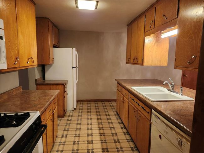 Kitchen with sink, white appliances, and light tile floors | Image 4