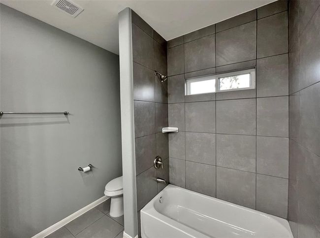 The room is accented by large tiles and a built-in bathtub, offering a stylish and functional space. | Image 11
