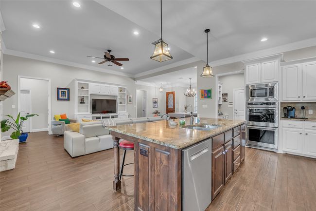 Kitchen with stainless steel appliances, a sink, recessed lighting, white cabinets, and wood finished floors | Image 13