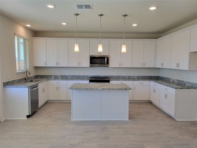 Kitchen with white cabinetry, stainless steel appliances, a sink, visible vents, and wood tiled floor | Image 7