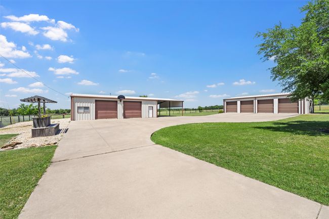 View of front of property with fence, a front lawn, board and batten siding, an outbuilding, and a detached garage | Image 30