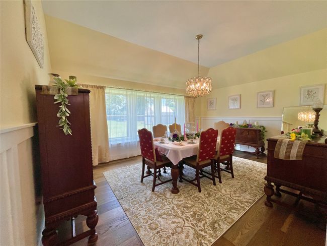 Dining area featuring a chandelier, wood finished floors, lofted ceiling, and a wainscoted wall | Image 14