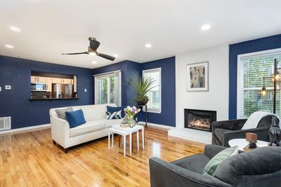 Living room featuring a large fireplace, light hardwood / wood-style flooring, and ceiling fan | Image 1