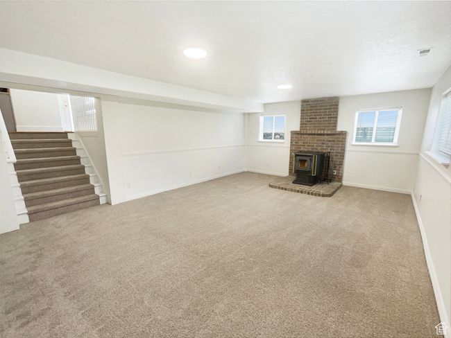 Unfurnished living room with stairway, carpet flooring, a wood stove, and visible vents | Image 21
