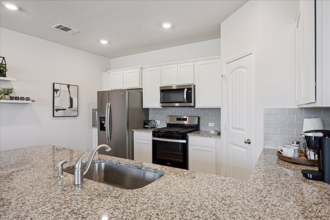 Kitchen featuring appliances with stainless steel finishes, backsplash, light stone counters, white cabinets, and recessed lighting | Image 23