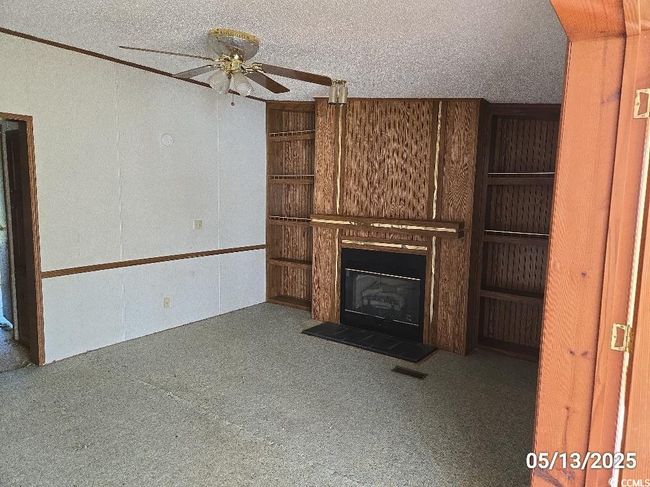 Unfurnished living room featuring ceiling fan, a glass covered fireplace, and carpet | Image 28