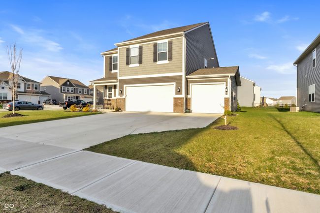 view of front of home with a front yard, brick siding, an attached garage, concrete driveway, and a residential view | Image 37