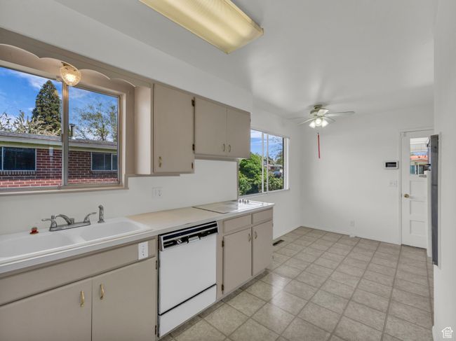 Kitchen with ceiling fan, light countertops, dishwasher, and a sink | Image 7